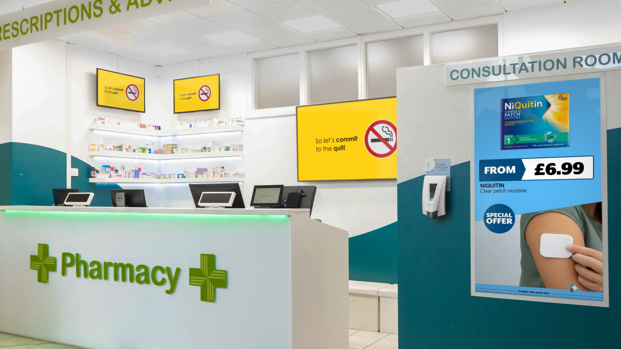 Pharmacy front desk showing 3 TV's in back displaying graphic image mounted on the walls 